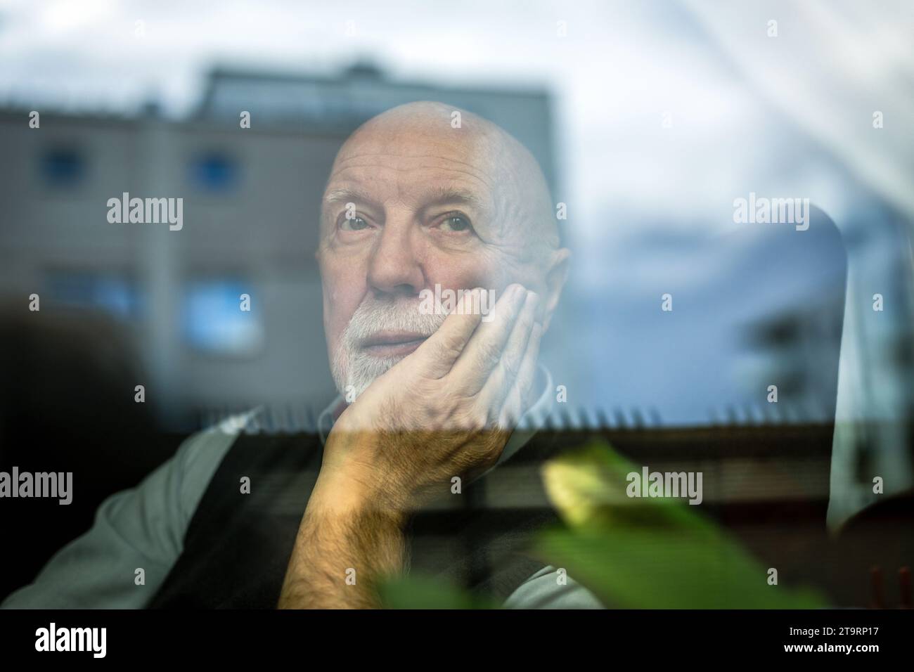 Porträt eines nachdenklichen älteren Mannes, der durch das Fenster schaut Stockfoto