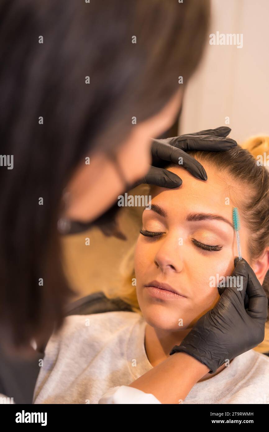 Vertikale Nahaufnahme der Rückansicht eines Friseurs, der die Augenbrauen eines Kunden durchkämmt Stockfoto