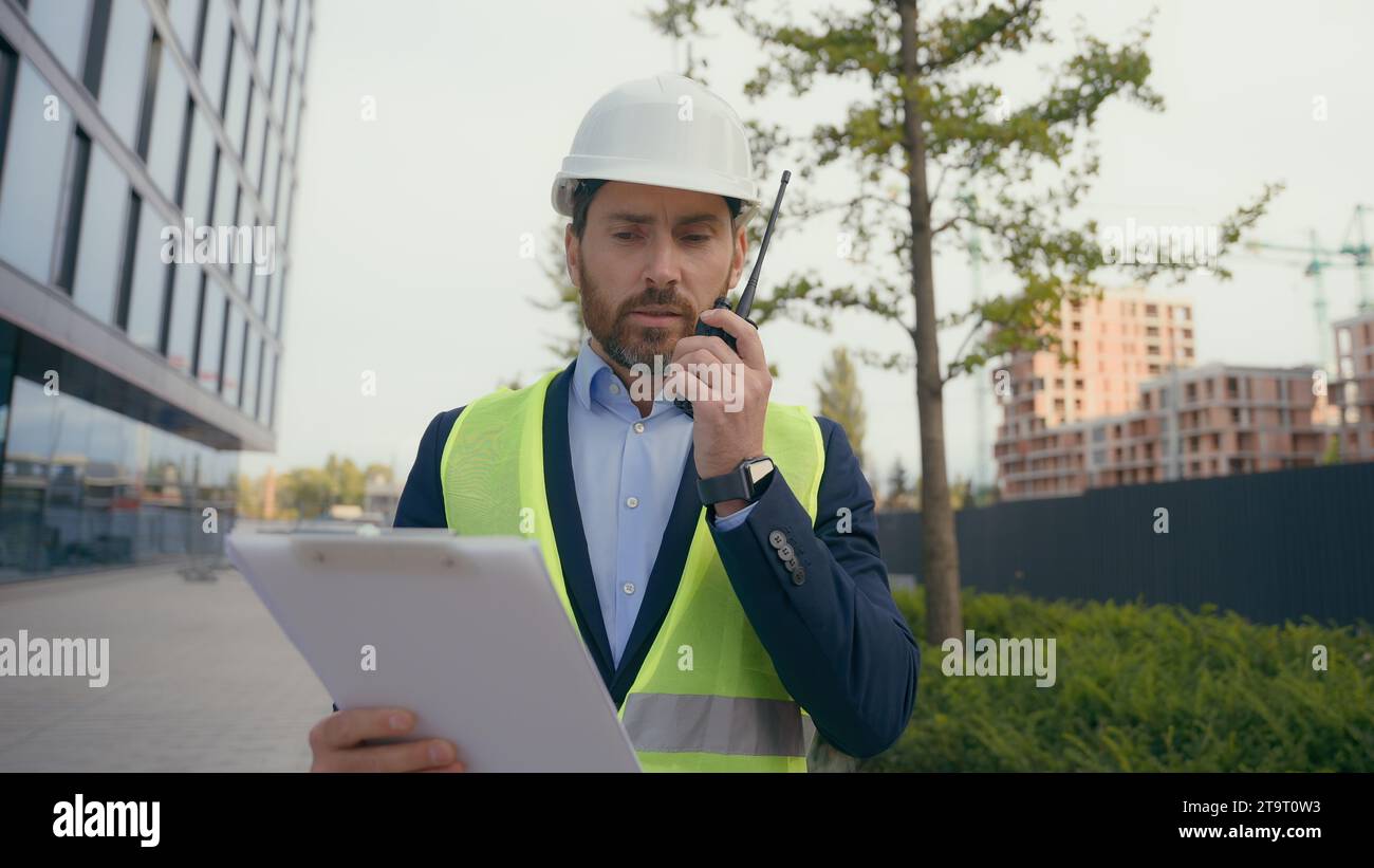 Kaukasischer professioneller Bauarbeiter Arbeiter im Walkie Talkie Baumeister mittleren Alters in Hard hat Talk Remote Radio man Architekt Ingenieur Stockfoto