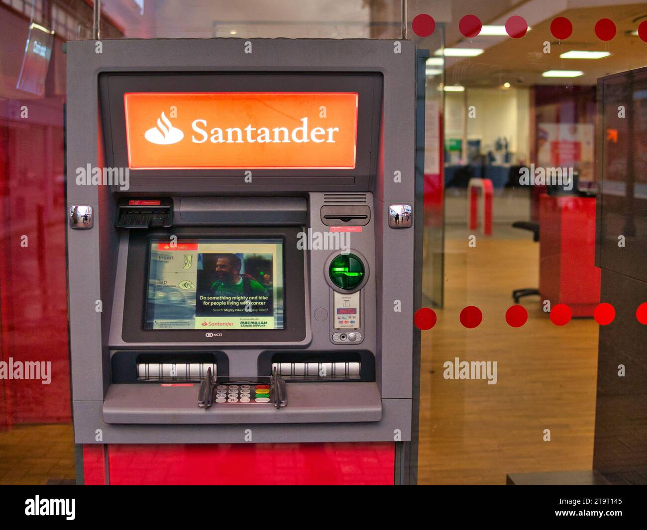 Ein Geldautomat außerhalb einer Filiale von Santander in Großbritannien. Das Innere der Bank ist im Hintergrund sichtbar. Stockfoto