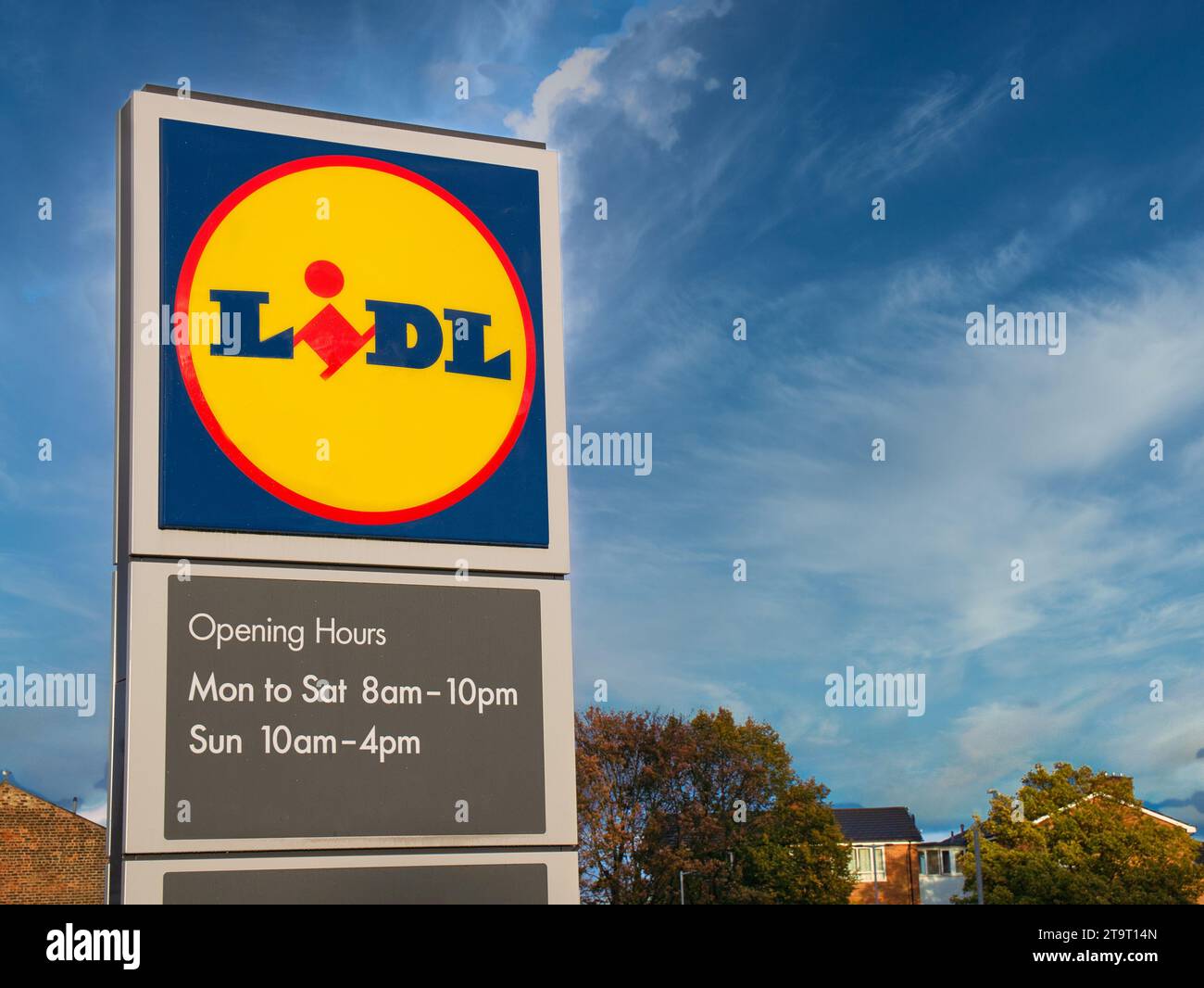 Firmenschilder vor einem Lidl-Supermarkt in Großbritannien. Das Schild enthält das gelbe, rote und blaue Firmenlogo sowie Angaben zu den Öffnungszeiten. Stockfoto