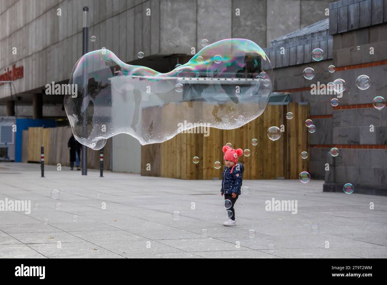 Kind, das große Seifenblasen in der Nähe des Doms in Köln ansieht. ###NUR REDAKTIONELLE VERWENDUNG### freundliche Bestaunung großer Seifenblasen nahe Dom, Ko Stockfoto