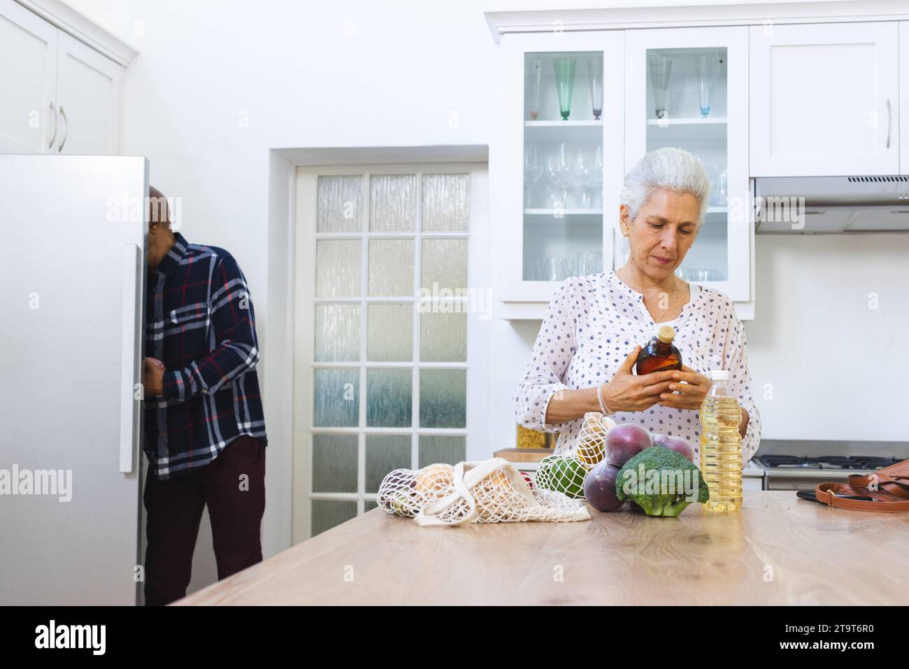 Diverse Seniorenpaare packen Lebensmittel in der Küche aus. Lebensstil, Ruhestand, Seniorenleben, Einkaufen, Zweisamkeit und häusliches Leben, unverändert. Stockfoto
