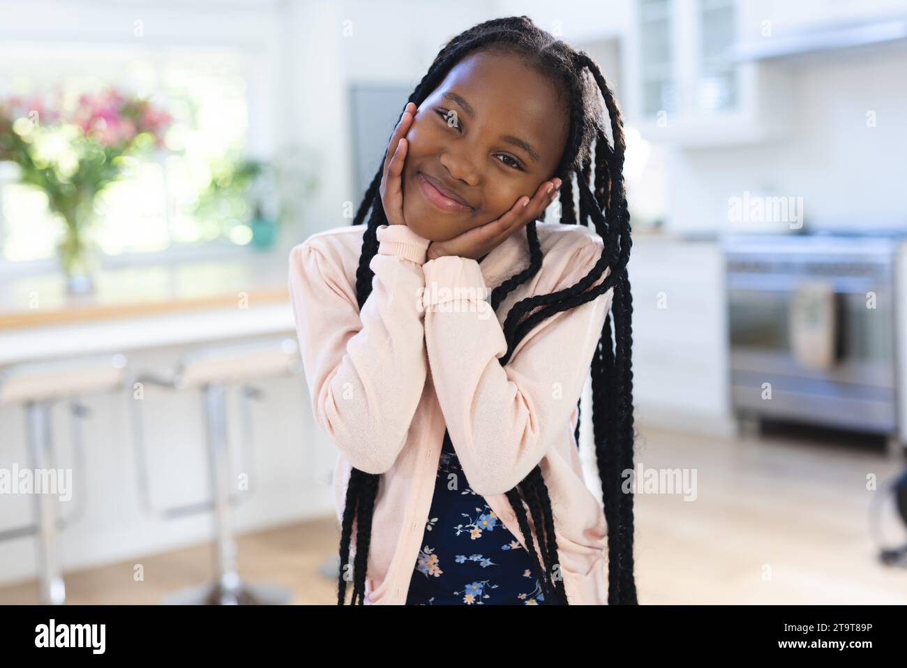 Glückliches afroamerikanisches Mädchen, das zu Hause mit Händen auf dem Gesicht steht, Kopierraum. Kindheit, Ausdruck, Gestikulation und häusliches Leben unverändert. Stockfoto