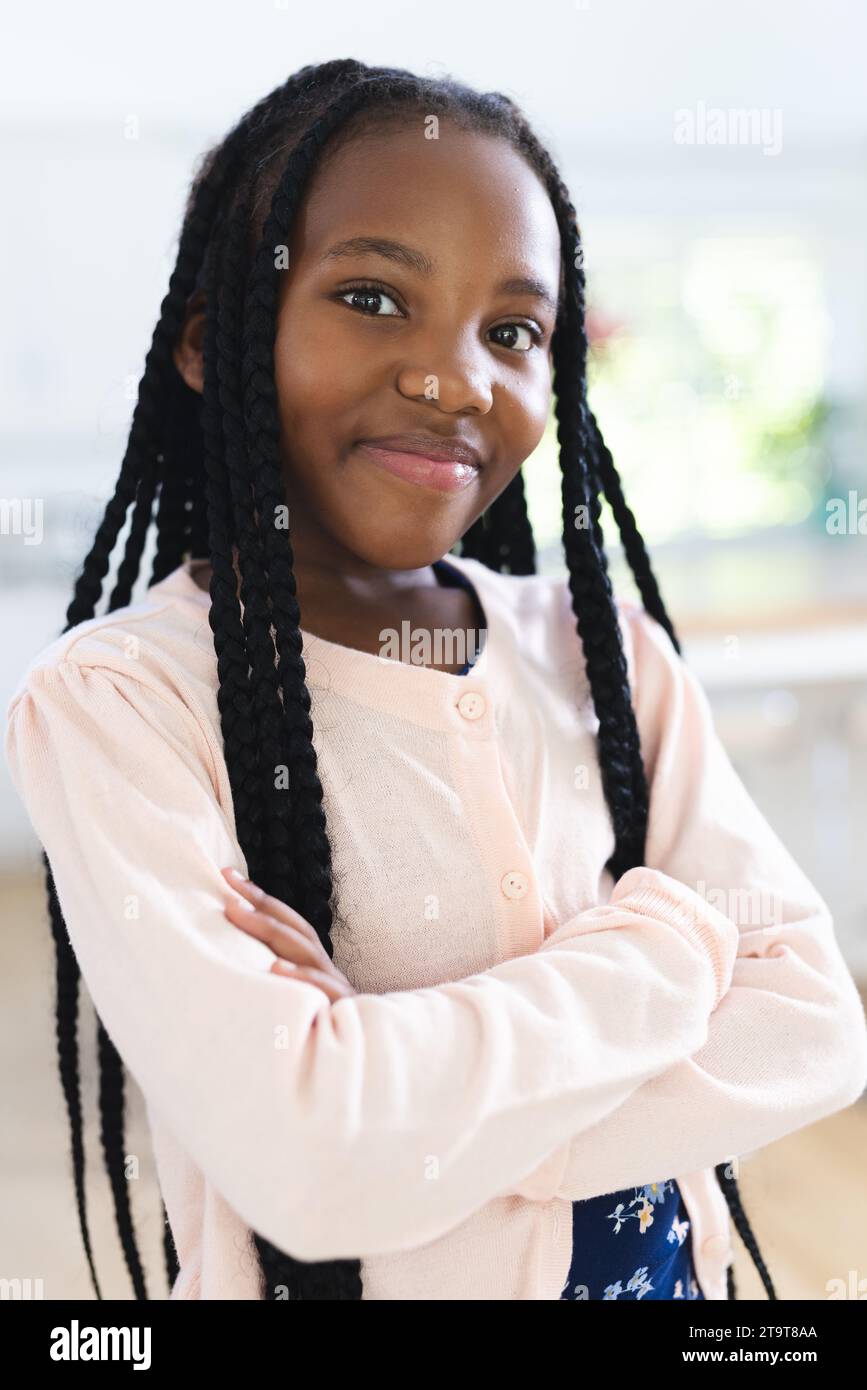 Glückliches afroamerikanisches Mädchen, das zu Hause mit gekreuzten Armen steht, Kopierraum. Kindheit, Ausdruck, Gestikulation und häusliches Leben unverändert. Stockfoto