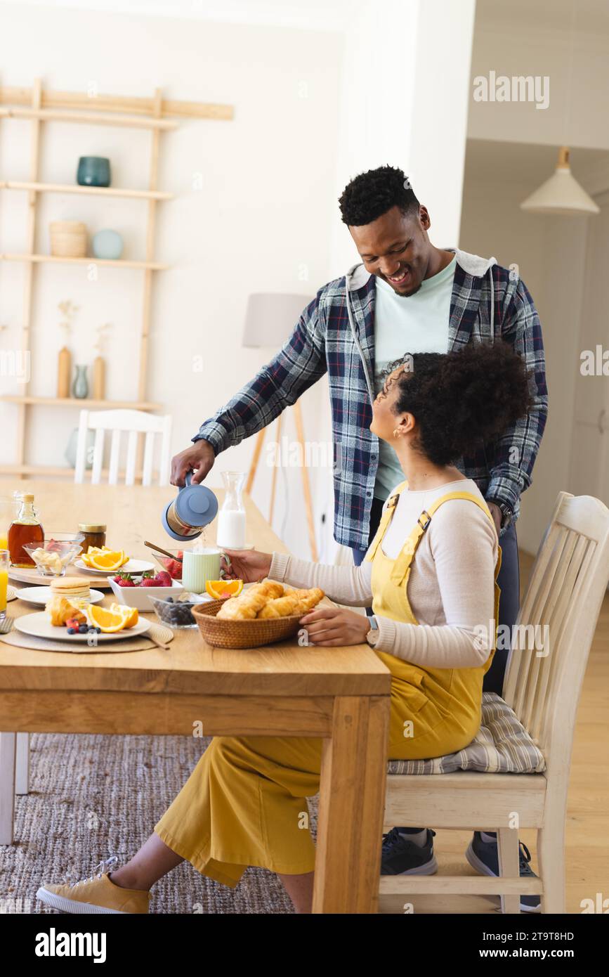 Glücklicher afroamerikanischer Mann, der morgens zu Hause Tee in eine Tasse zum Frühstück gießt, Kopierraum. Zweisamkeit, Elternschaft, Kindheit, Essen und Trinken, Domest Stockfoto