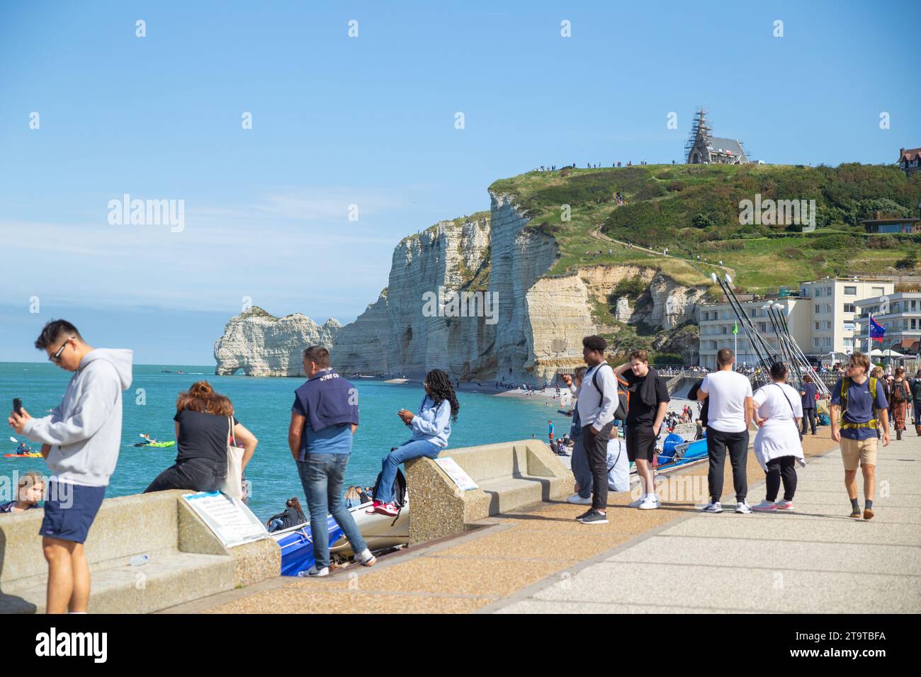 Etretat, Frankreich–September 2,2023: Touristen genießen Sonnenschein am Strand mit Klippen im Hintergrund Stockfoto