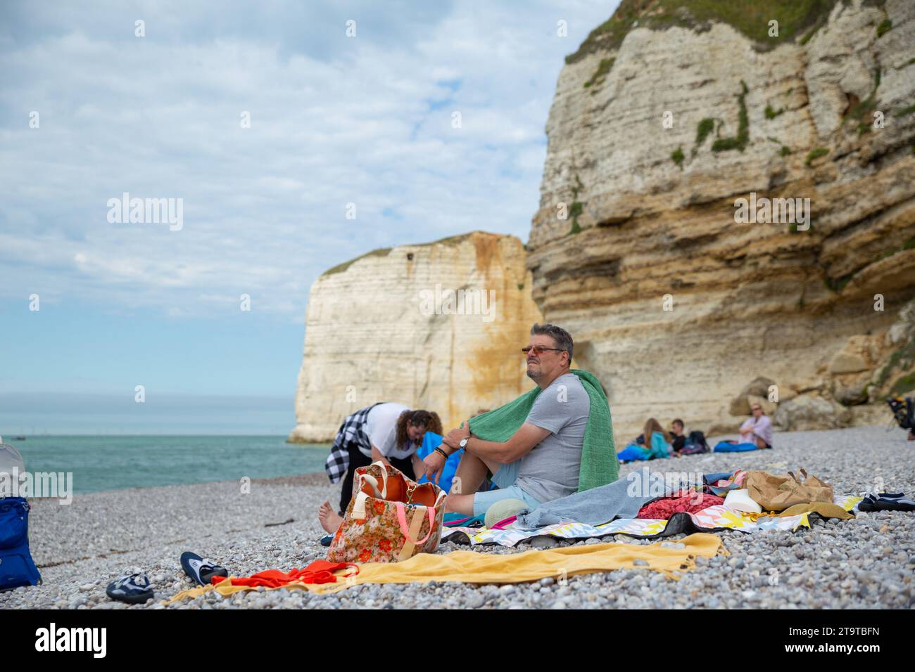 Etretat, Frankreich–September 2,2023: Touristen genießen Sonnenschein am Strand mit Klippen im Hintergrund Stockfoto