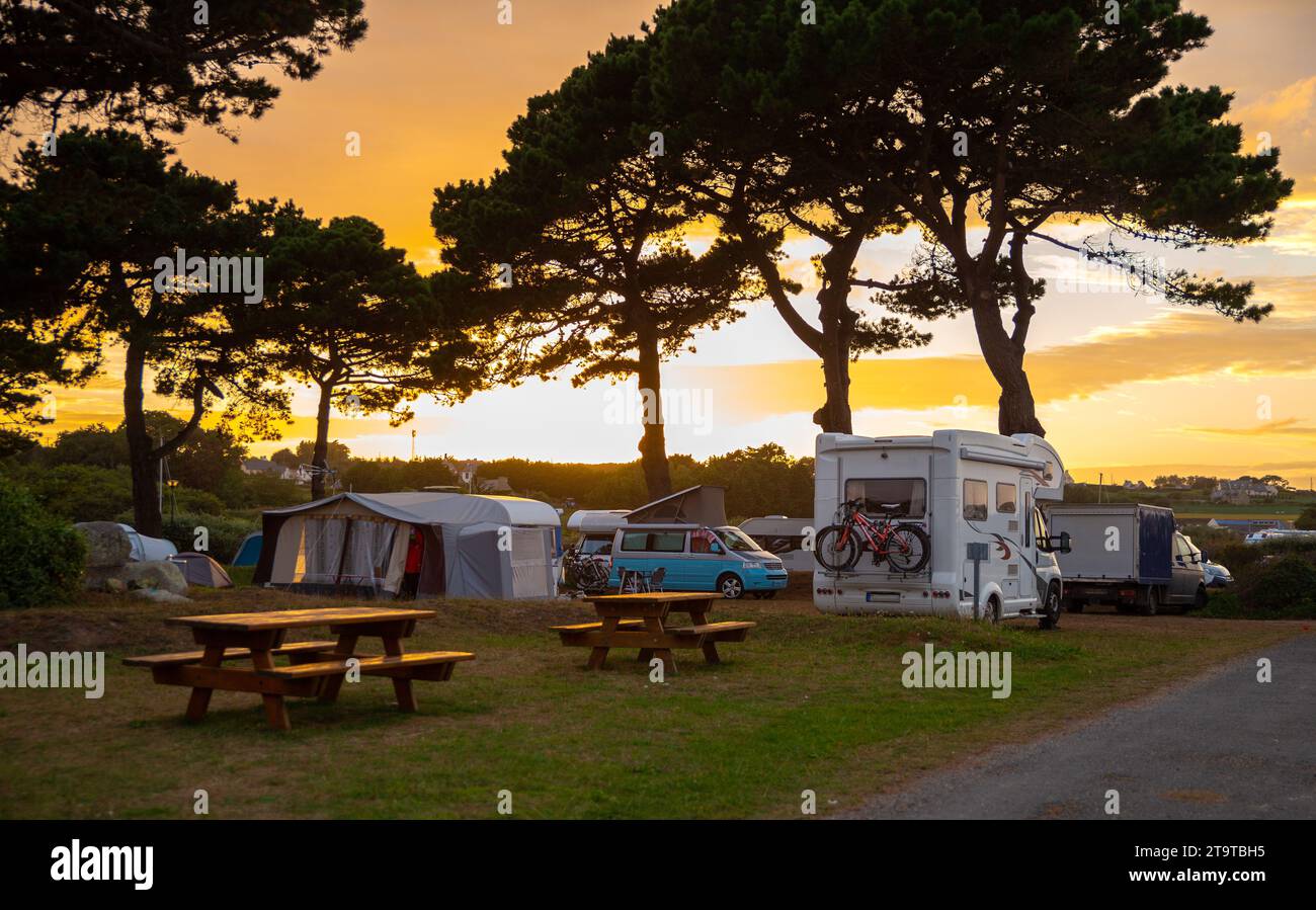 Ein wunderschöner Campingplatz voller Wohnmobile, Wohnwagen, Zelte und Picknicktisch mit dramatischem Sonnenuntergang Stockfoto