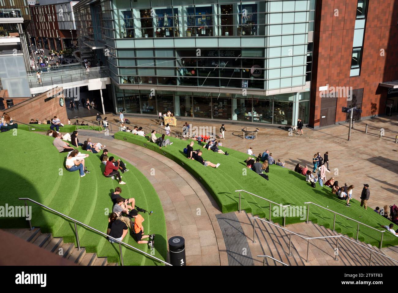 Shoppers Siiting auf Kunstrasen-Terrassen im Liverpool One City Centre Shopping Centre & dem modernen John Lewis Building Liverpool England UK Stockfoto