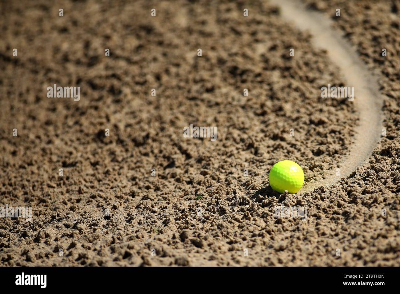 Ein gelber Golfball rollt im Sandbunker. Stockfoto