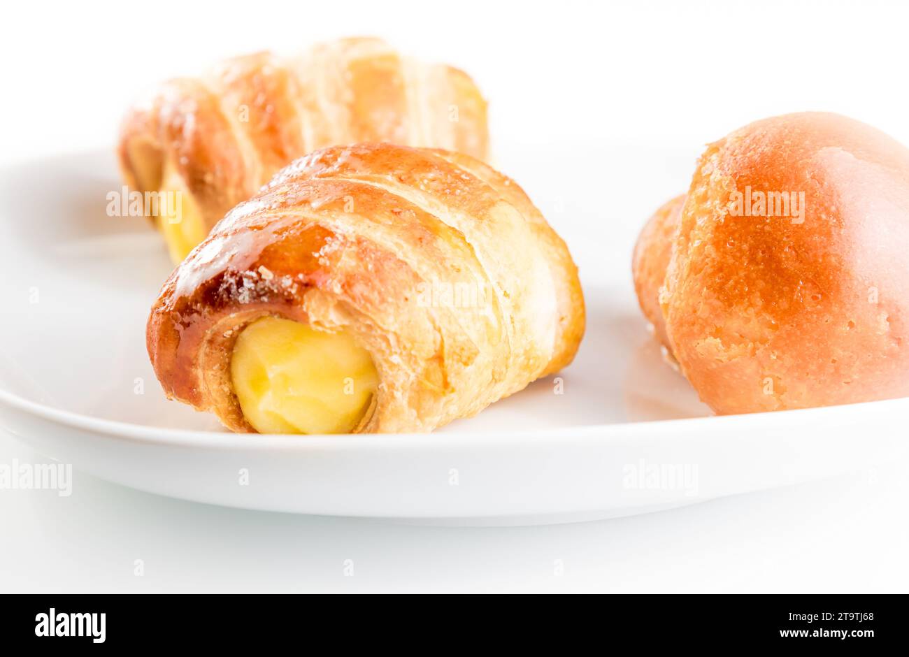 Köstliche Cannoli gefüllt mit Creme und Rum babà auf weißem Hintergrund Stockfoto