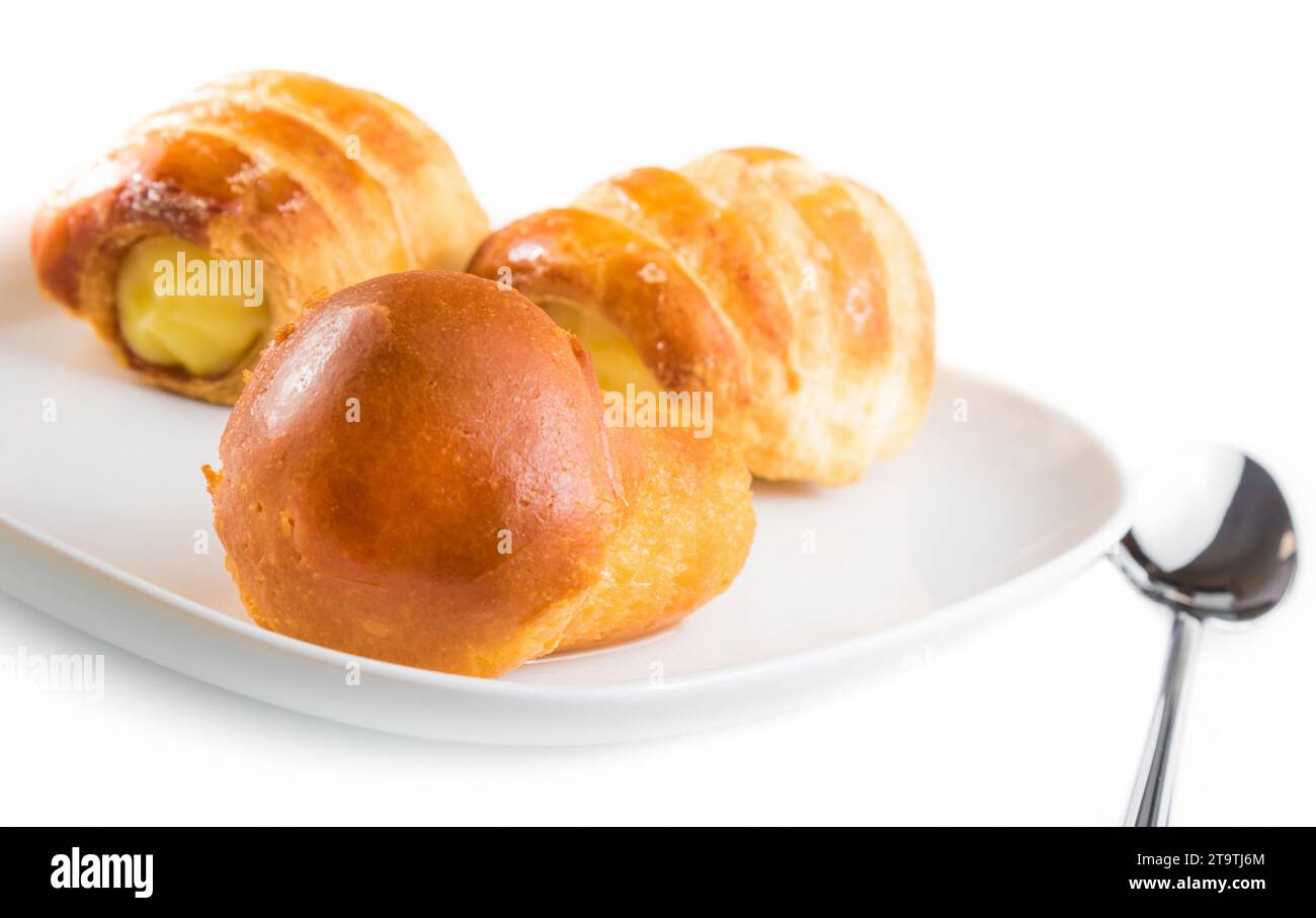 Köstlicher Rum babà in der Nähe von Cannoli gefüllt mit Creme auf weißem Hintergrund Stockfoto