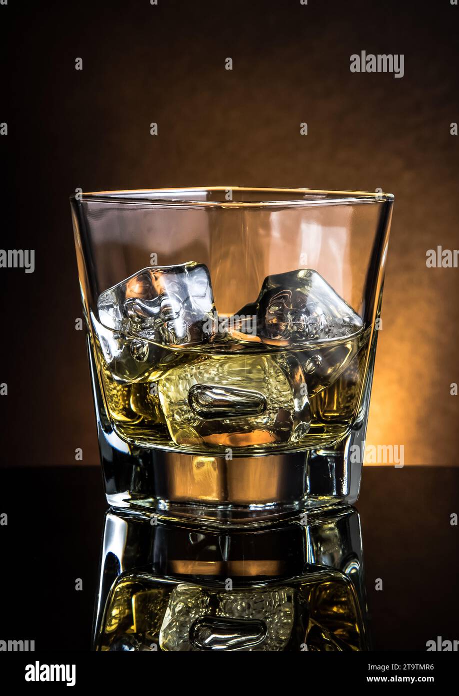 Glas Whiskey auf schwarzem Tisch mit Reflexion, warme Atmosphäre, dunkles Licht, Zeit der Entspannung mit Whisky Stockfoto