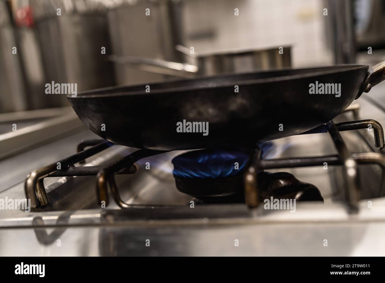 Bratpfanne mit blauen Flammen aus einem professionellen Küchenherd. Gaskocher mit brennenden Flammen von Propangas. Industrial Luxury Hotelküche Stockfoto