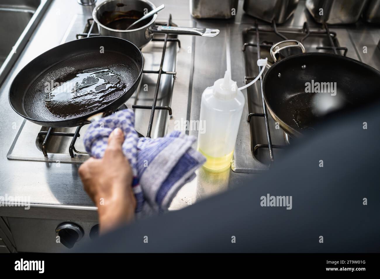 Koch-Schaukeln ölen Sie eine beheizte Skillet im Restaurant. Bild des Kochkonzepts des Luxushotels. Stockfoto