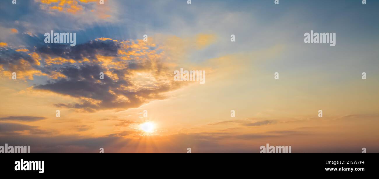 Sonnenuntergangsszene mit Sonnenuntergang und Strahlungslicht, Wolken im Hintergrund, warmer bunter Himmel mit weichen Wolken Stockfoto