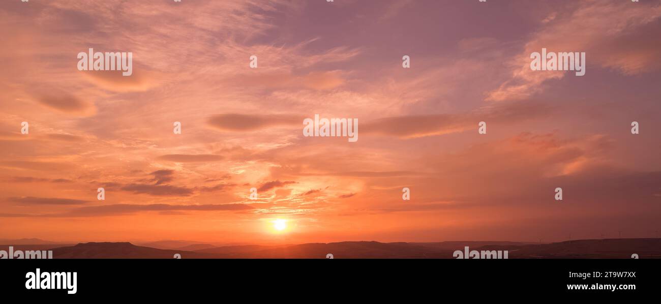 Sonnenuntergangsszene mit Sonnenuntergang und Strahlungslicht, Wolken im Hintergrund, warmer bunter Himmel mit weichen Wolken Stockfoto