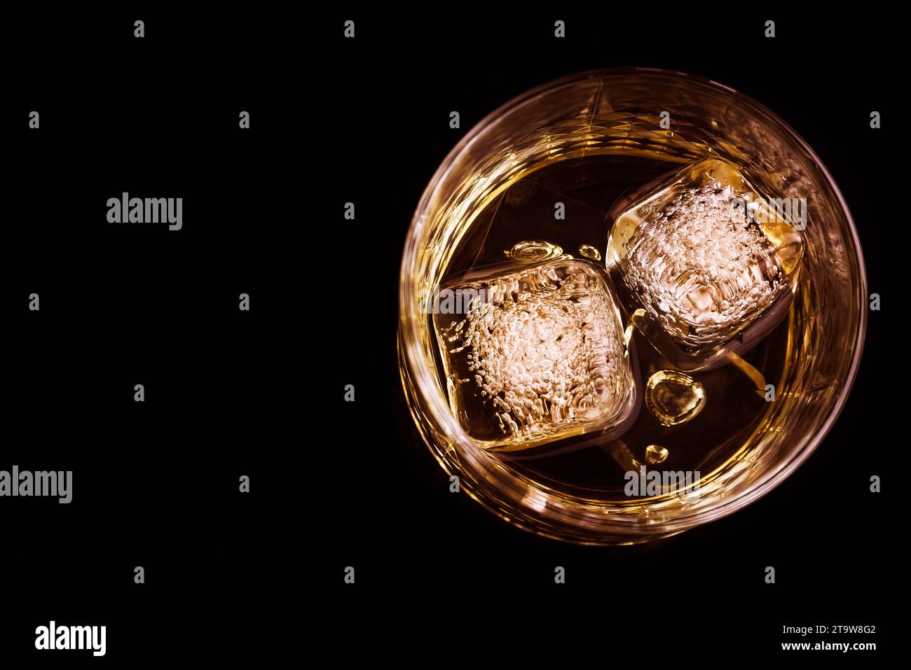 Blick von oben auf Whiskey im Glas mit Eiswürfeln auf schwarzem Hintergrund, Fokus auf Eiswürfeln, Whisky Relax Zeit Stockfoto