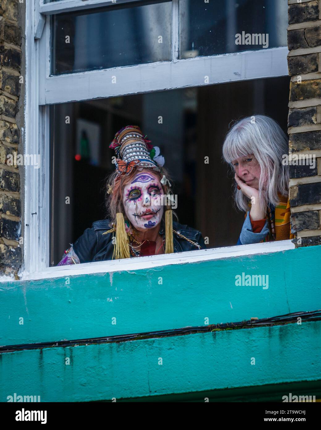Bemalte Gesichter sehen Sie das „DIA de los muertos“-Ereignis von einem Fenster auf der berühmten Columbia Road in London aus. Stockfoto
