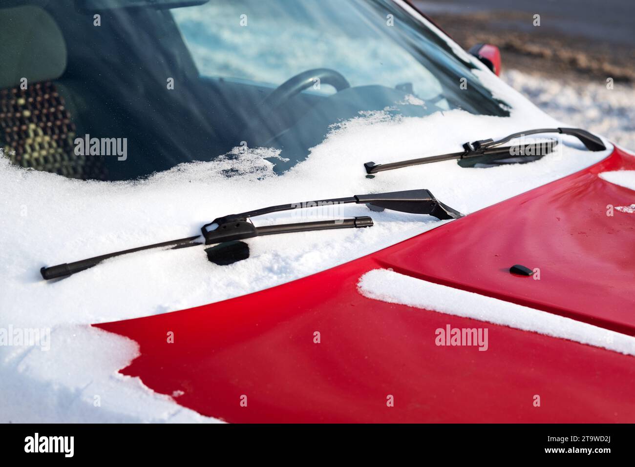 Nahaufnahme der gefrorenen Windschutzscheibe und des roten Scheibenwischers im Winter Stockfoto
