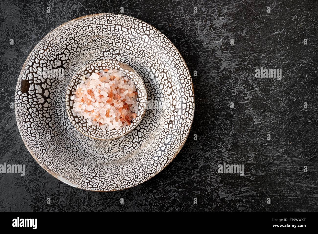 Rosa Himalaya-Salz in Kristallen auf einer eleganten, handgefertigten Platte. Himalaya rosa Salz zum Essen und Baden. Draufsicht, flach. Kopierbereich. Stockfoto