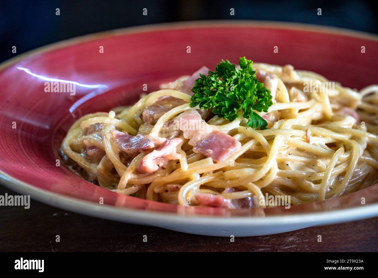 Eine frisch zubereitete Spaghetti Carbonara, serviert in einer roten Schüssel Stockfoto