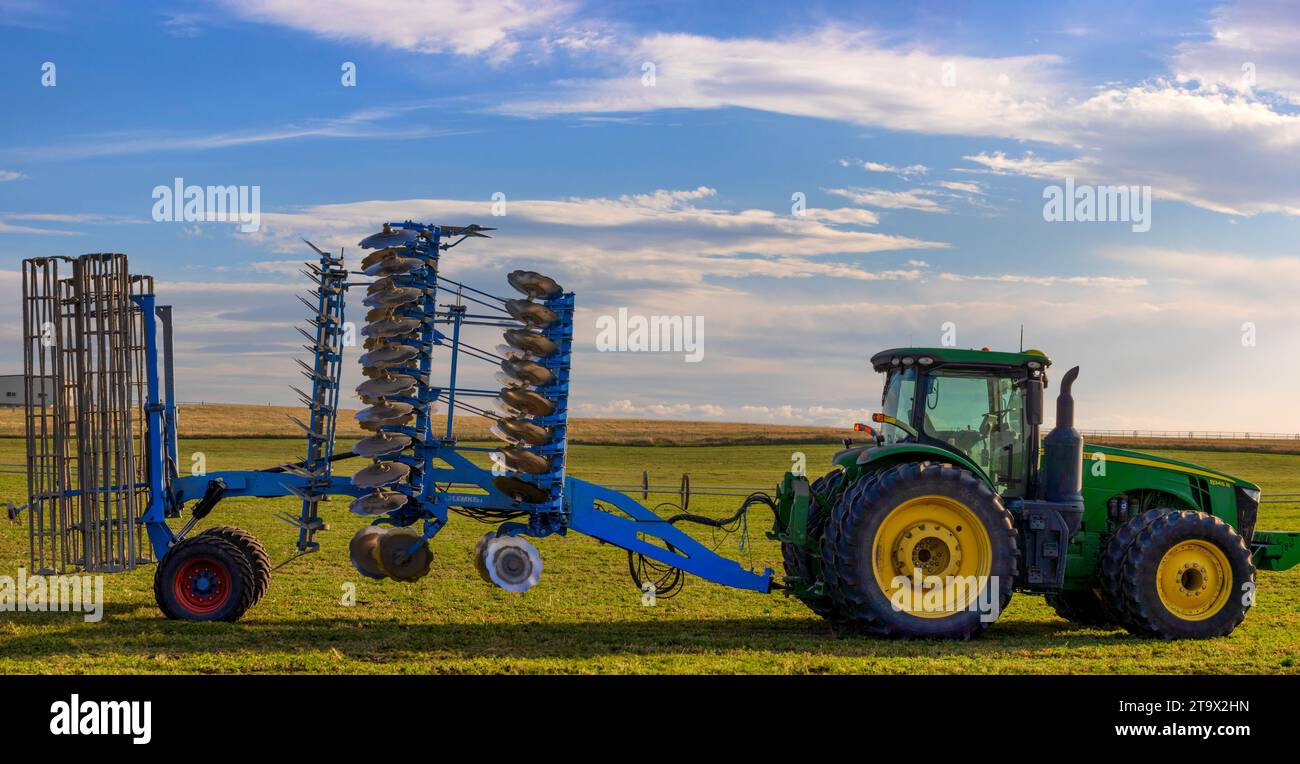 Landwirtschaftsbild eines Trackers mit angebrachtem Arbeitsgerät auf einem Luzerne-Feld Stockfoto