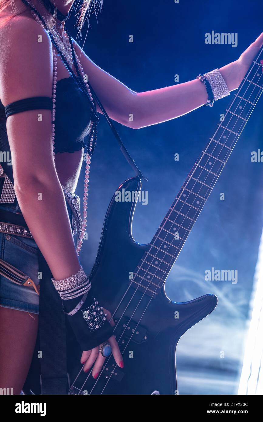 Eine Frau in Rockmode greift ihre Bassgitarre mit einem entschlossenen Look Stockfoto