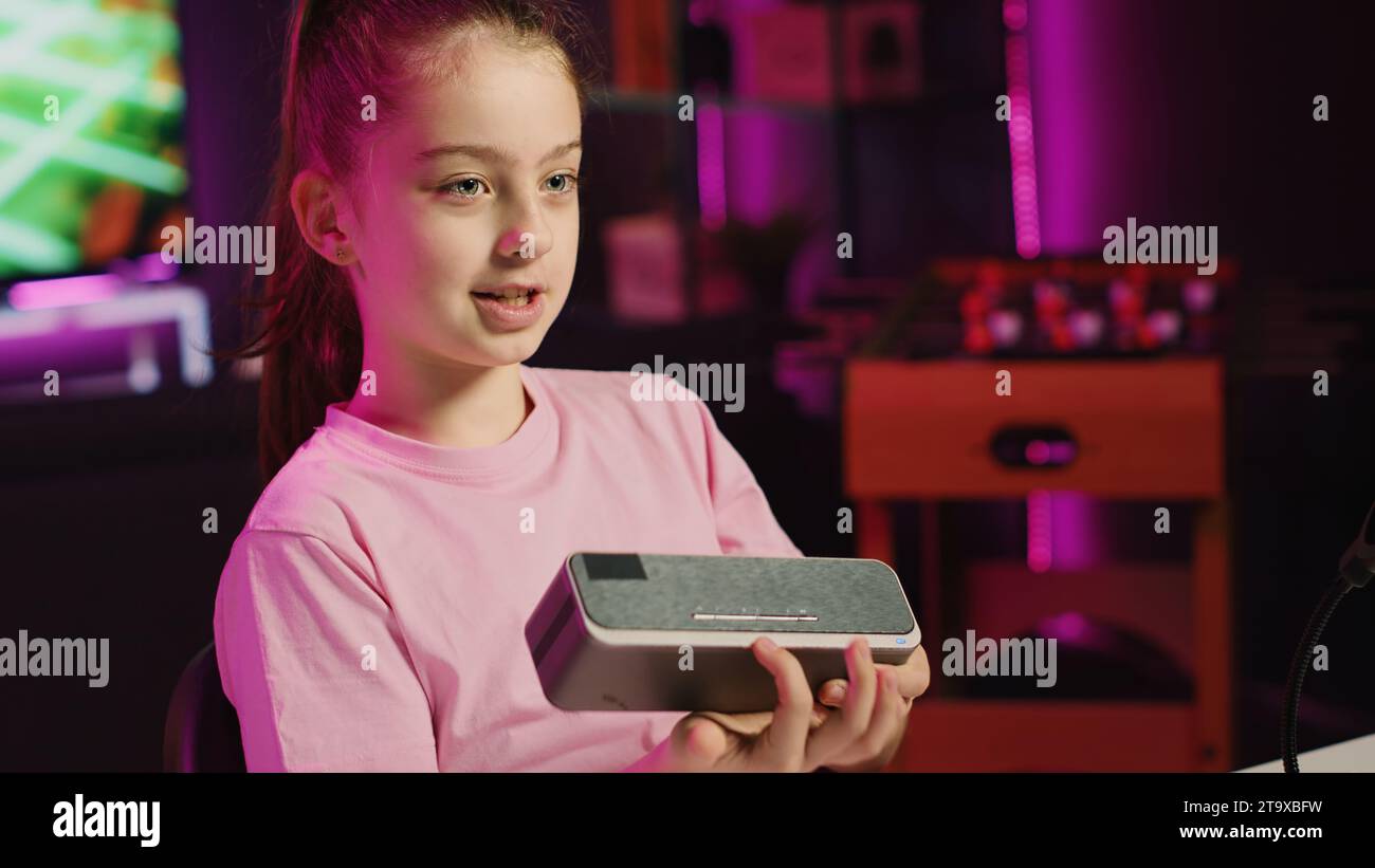 Entertainer für junge Kinder, der die Technologie eines tragbaren Bluetooth-Lautsprechers für Online-Streaming-Kanal überprüft. Kinder-Influencer Filme Musik-Spielgerät-Unboxing für Generation Z Publikum Stockfoto