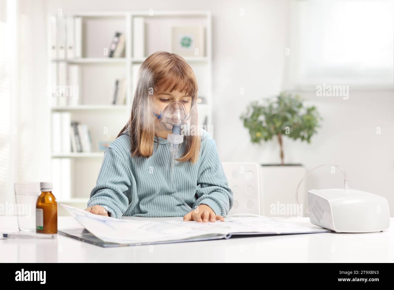 Ein kleines Mädchen liest ein Buch und benutzt zu Hause einen Vernebler mit Dampfnebel Stockfoto