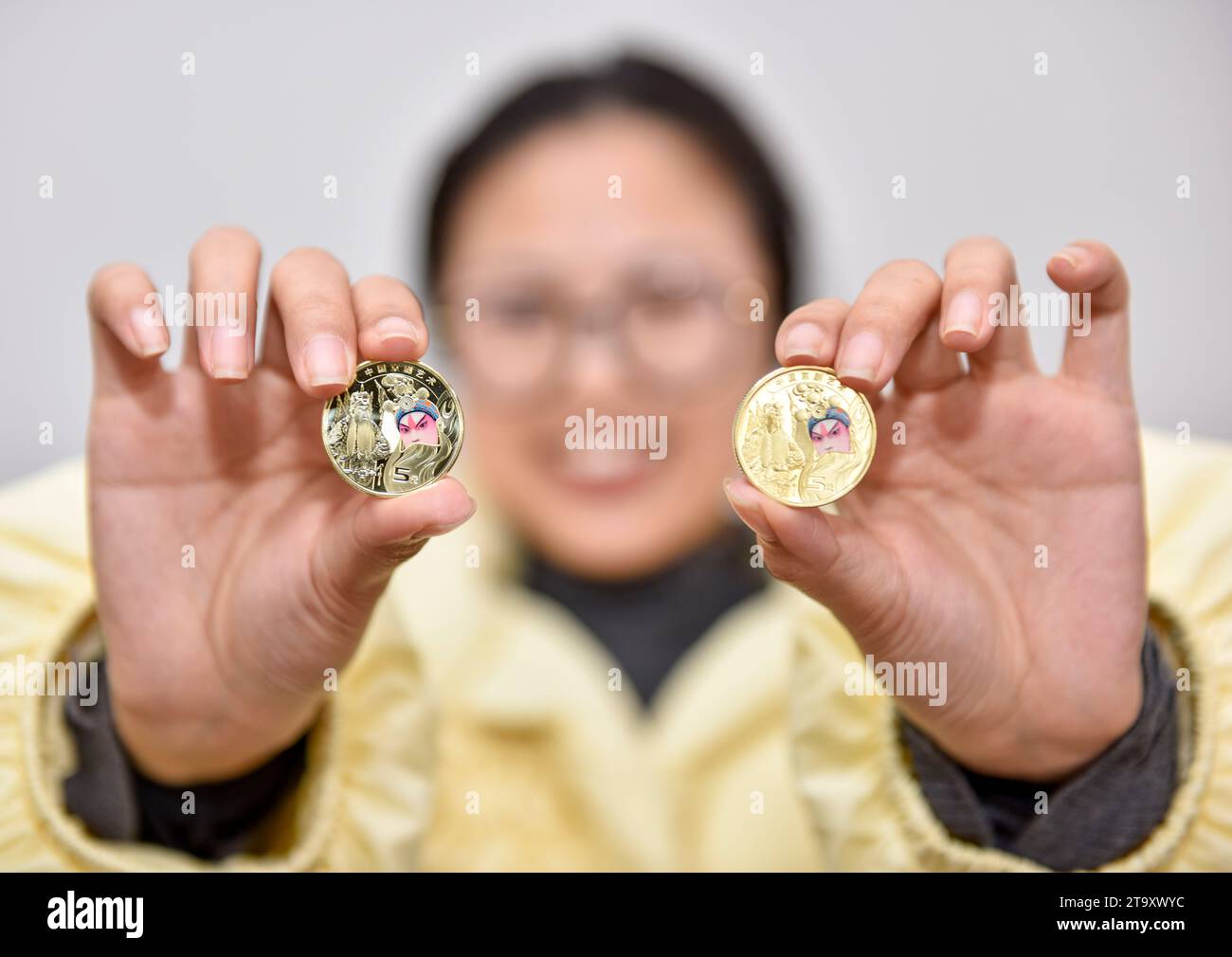 Ein chinesischer Bürger zeigt eine Gedenkmünze für die Peking Oper in Huai'an, Provinz Jiangsu, China, 28. November 2023. Stockfoto