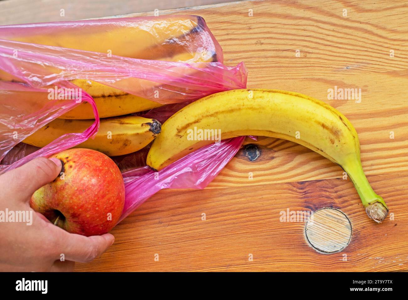 Nehmen Sie Bananen aus einem Einweg-Plastikbeutel auf eine Holzoberfläche. Umweltökologen Stockfoto