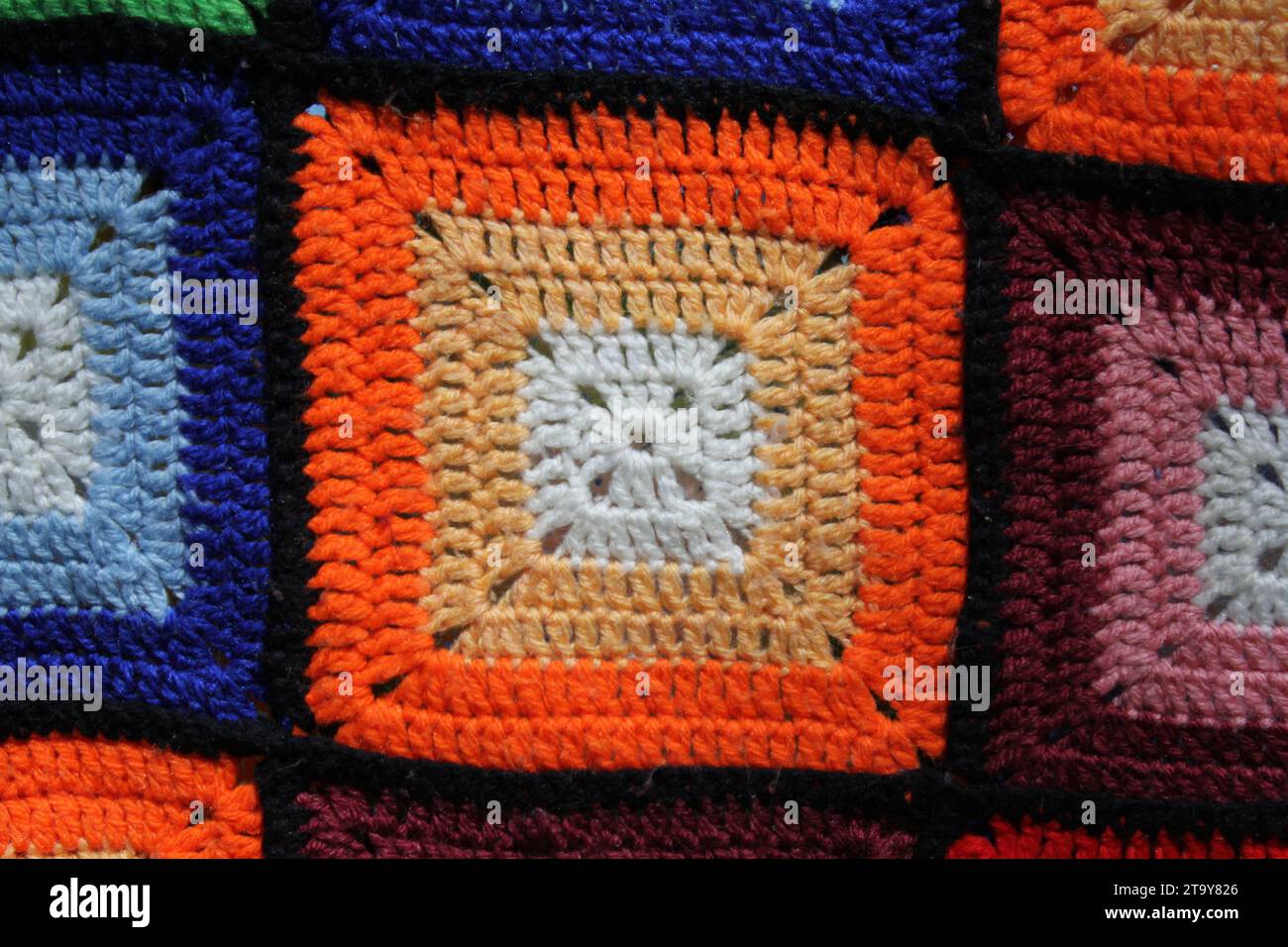 Nahaufnahme einer orangen, blauen und kastanienbraunen Strickdecke aus Wolle Stockfoto