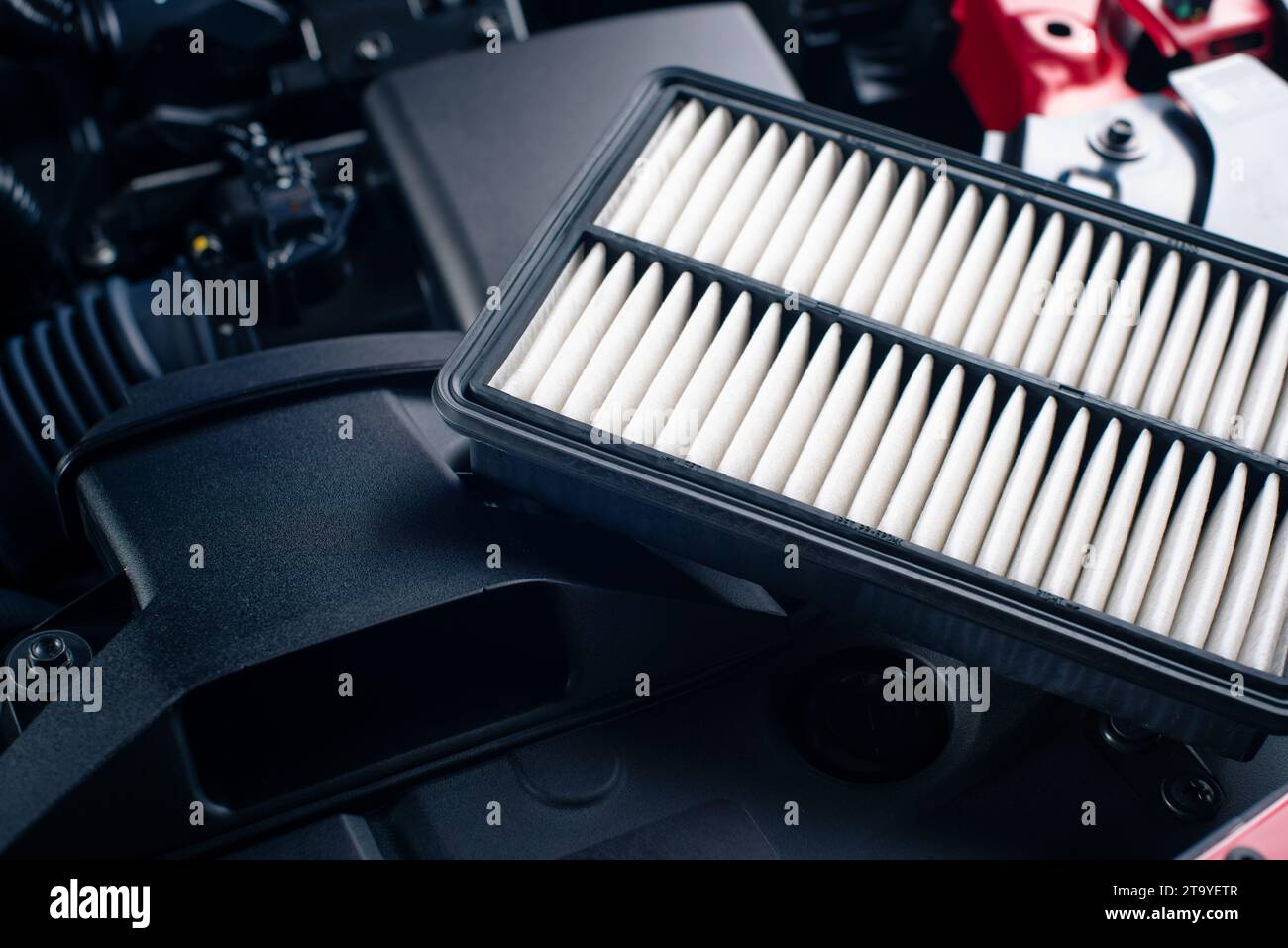 Fahrzeugluftfilter wechseln, Nahaufnahme des neuen und sauberen Luftfilters im Motorraum des roten Autos. Fahrzeugwartungskonzept. Stockfoto