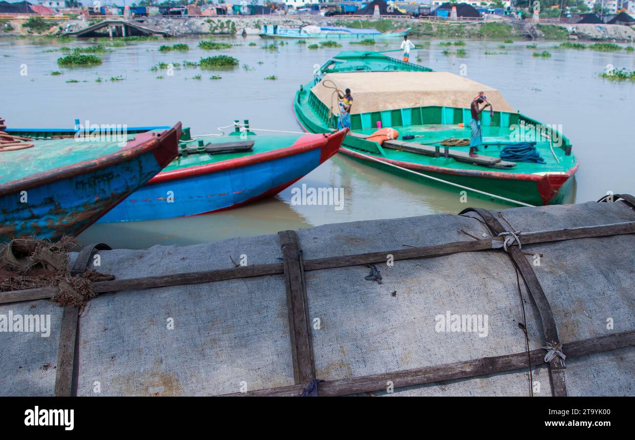 Traditionelle Frachtbootstation am Ufer. Eine malerische Szene entfaltet sich entlang des Flusses von Bangladesch, während traditionelle Frachtschiffe Th finden Stockfoto