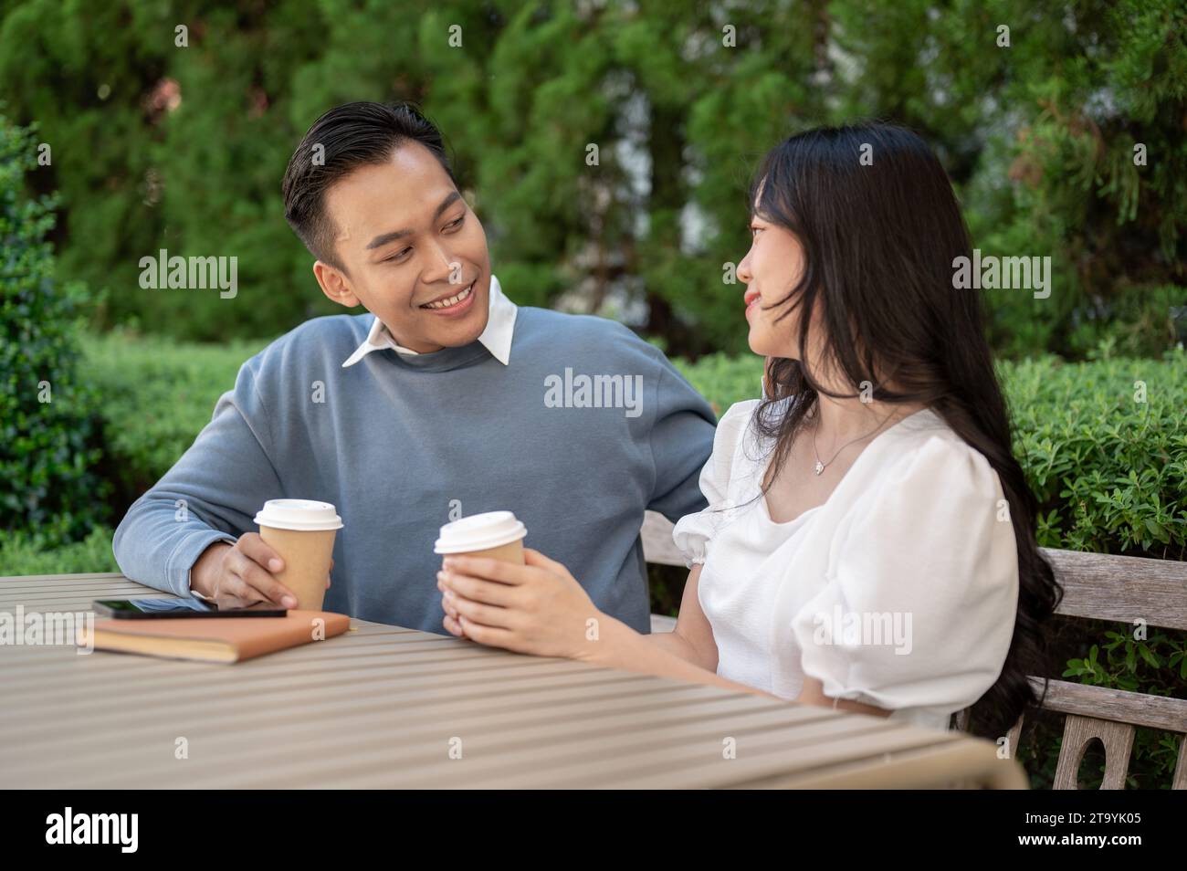 Das junge süße asiatische Paar verbringt Zeit zusammen im Park und sitzt dicht nebeneinander. Abhängen Stockfoto