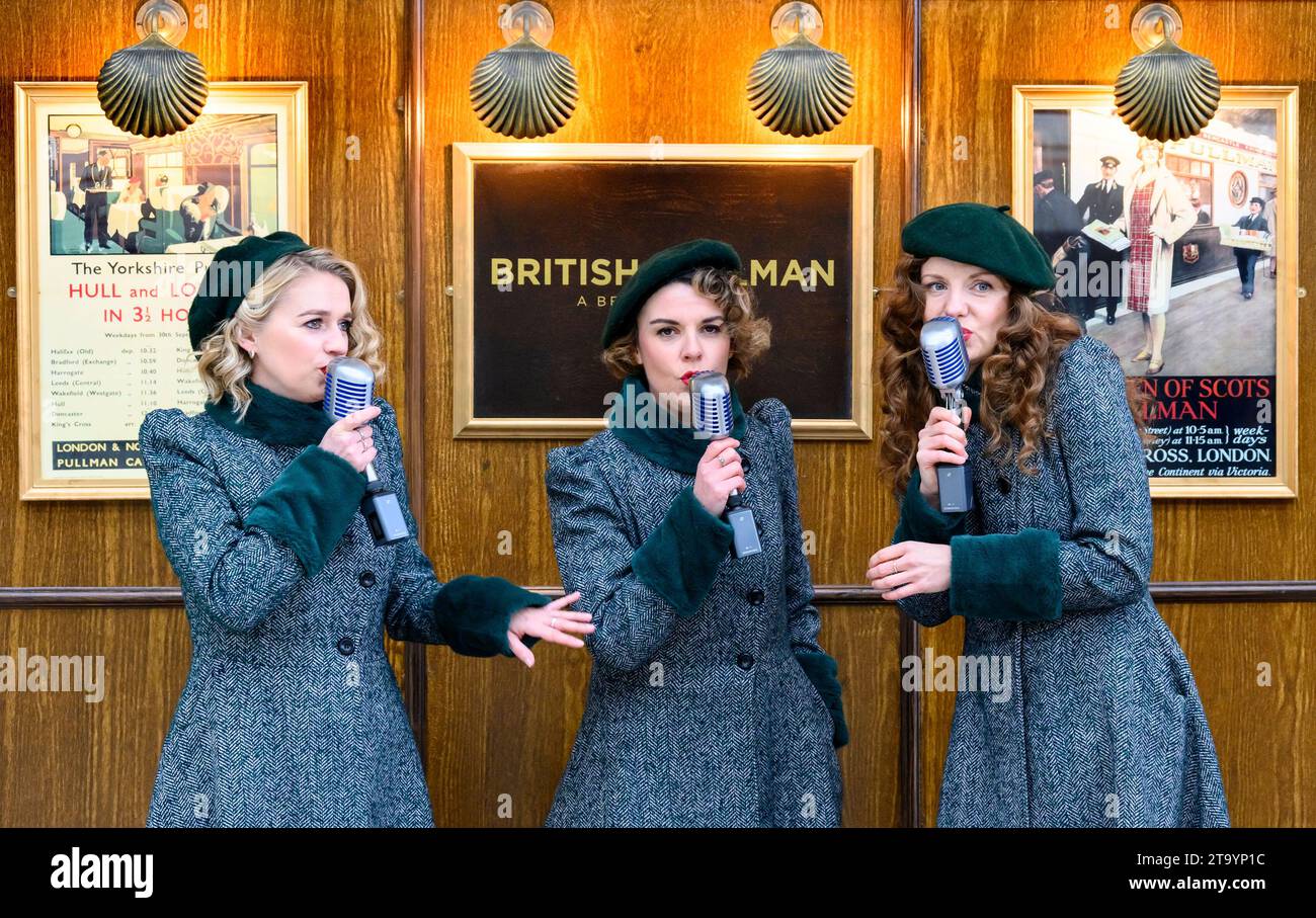 London, Großbritannien. Enge Harmonie Singers begrüßen Passagiere für den Orient Express auf Bahnsteig 1 am Bahnhof Victoria. November 2023 Stockfoto