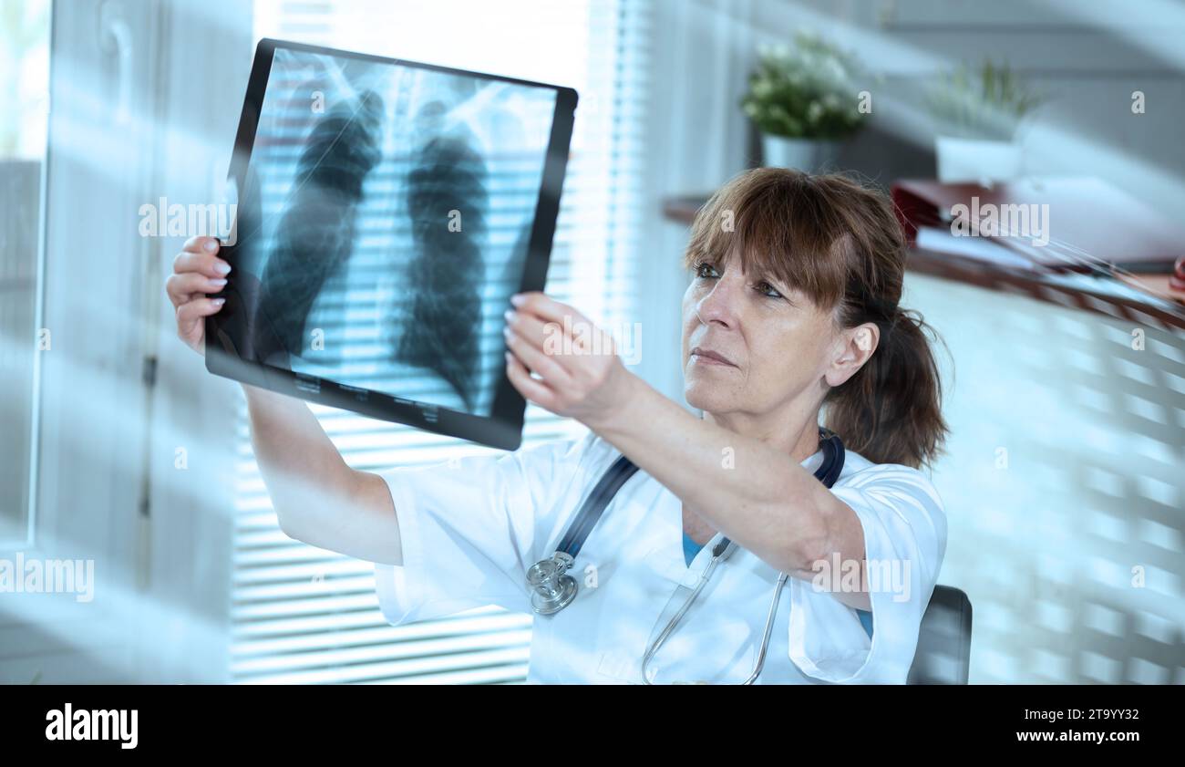 Ärztin, die Röntgenbericht in der Arztpraxis untersucht; Lichteffekt Stockfoto