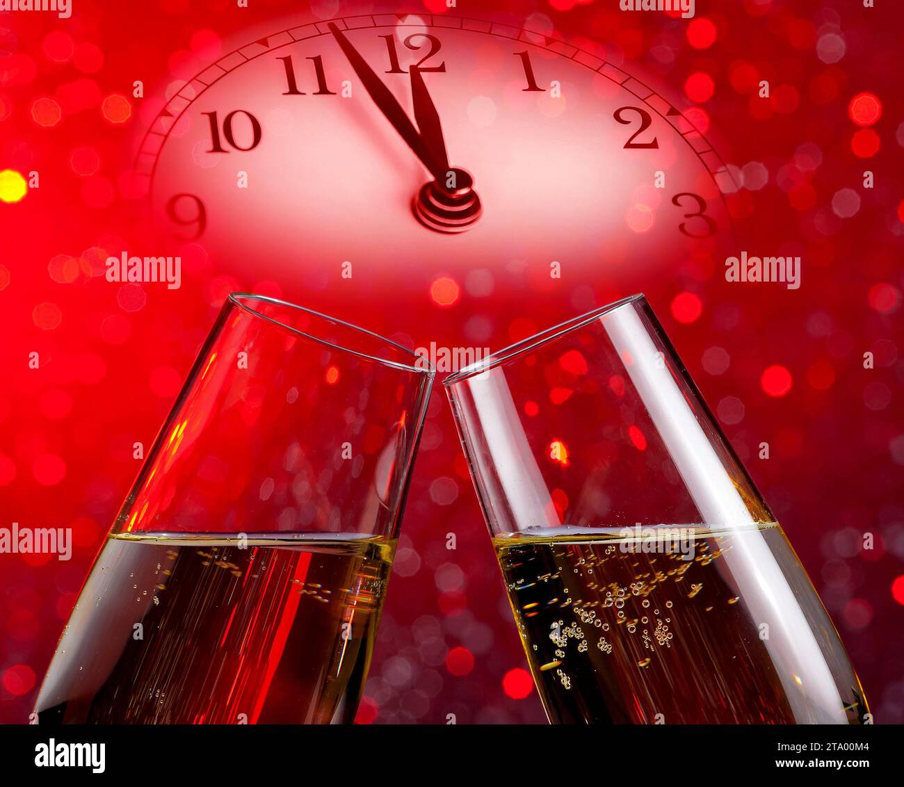 Champagnerflöten mit goldenen Blasen lassen auf rotem Bokeh-Hintergrund mit Vintage-Wecker jubeln, der mittags oder mitternacht ein Happy New Year-Konzept zeigt Stockfoto