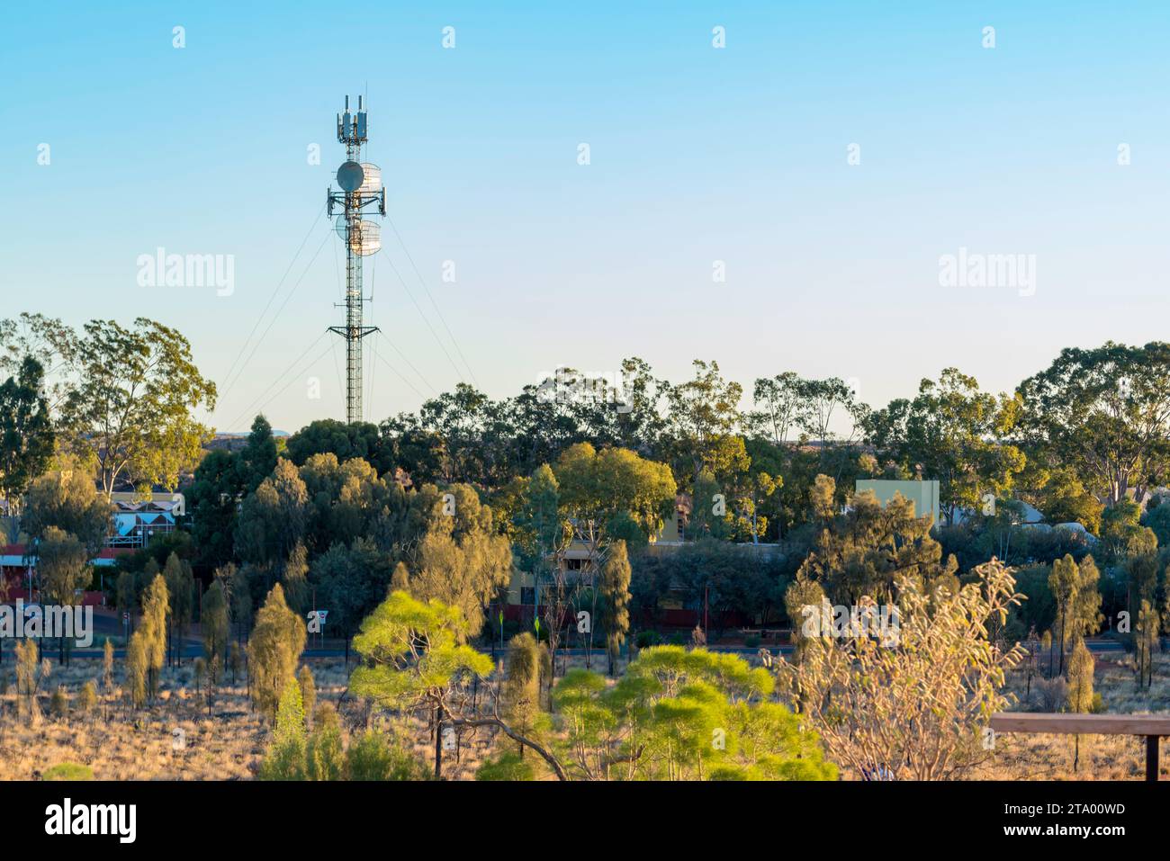 Bis auf den großen Satelliten- und Telekommunikationsturm ist das Ulara Ayers Rock Resort nahe Uluru in Australien fast von umliegenden Bäumen versteckt Stockfoto