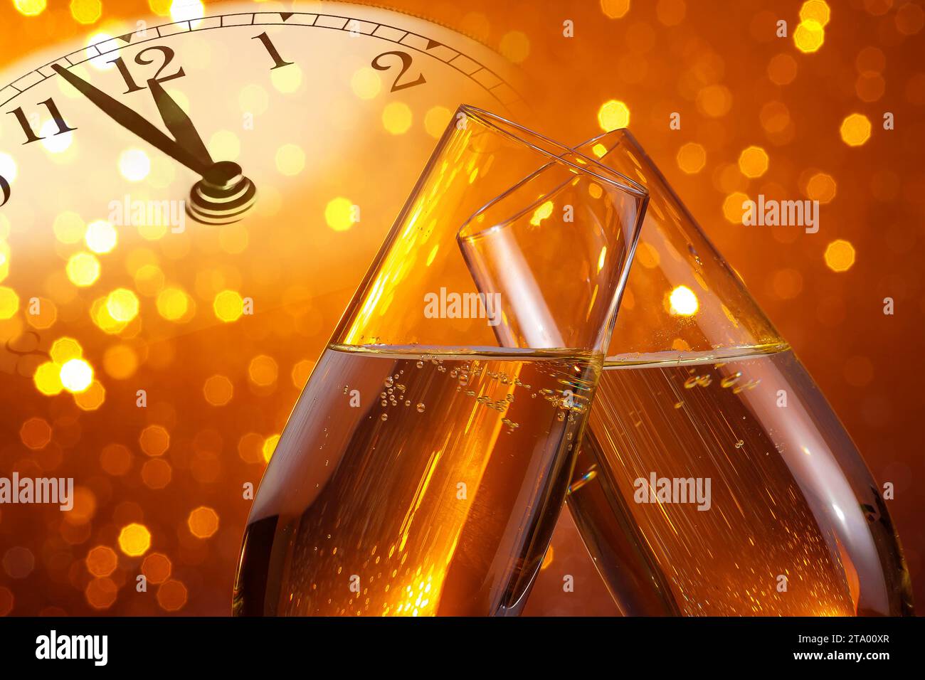 Champagnerflöten mit goldenen Blasen lassen auf goldenem Bokeh-Hintergrund mit Vintage-Wecker jubeln, das Mitternachtskonzept zeigt, ein Happy New Year Stockfoto