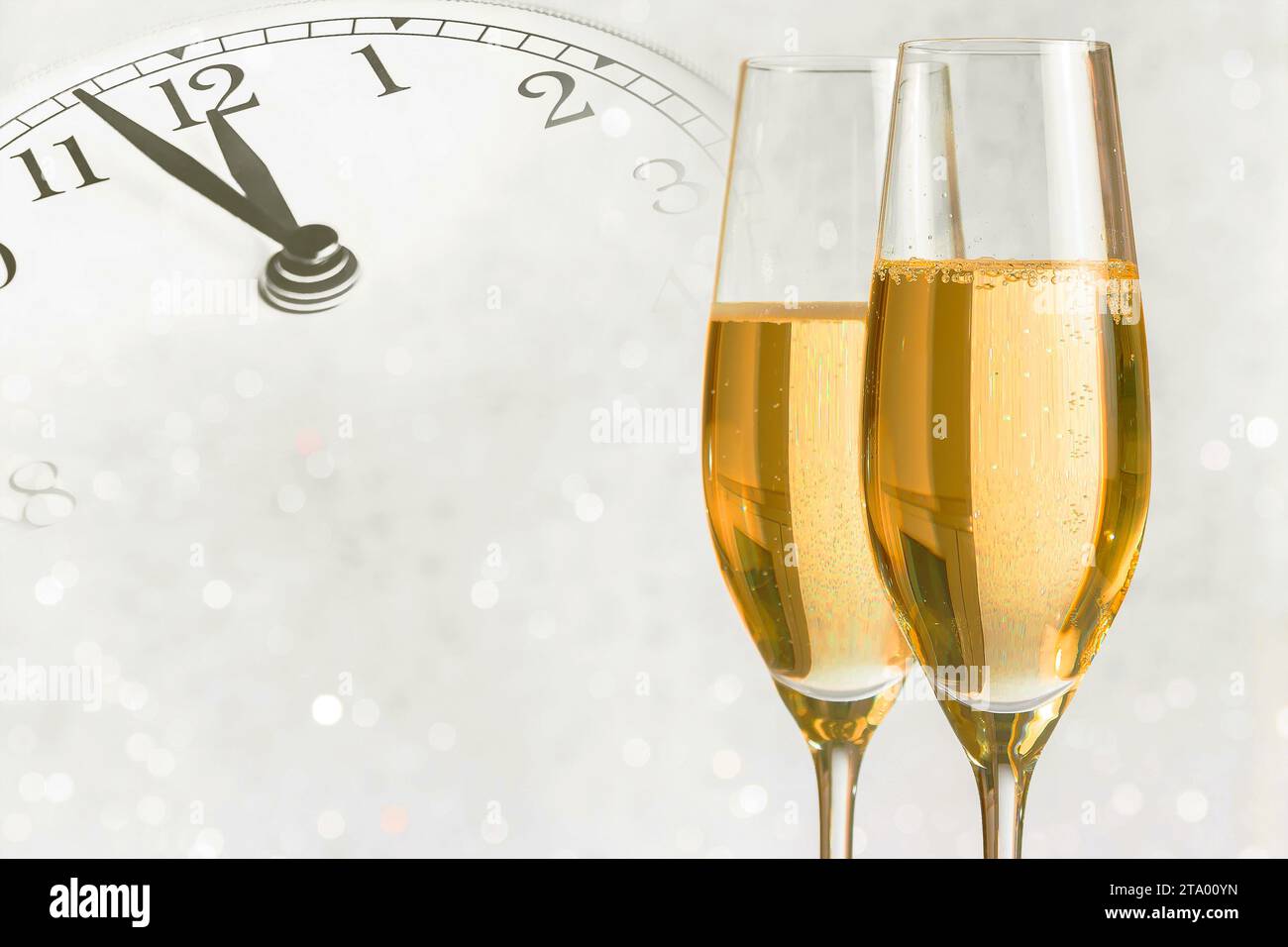 Champagnerflöten mit goldenen Blasen lassen auf silbernem Bokeh-Hintergrund mit Vintage-Wecker jubeln, der Mittag- oder Mitternacht zeigt, Happy New Year-Konzept Stockfoto