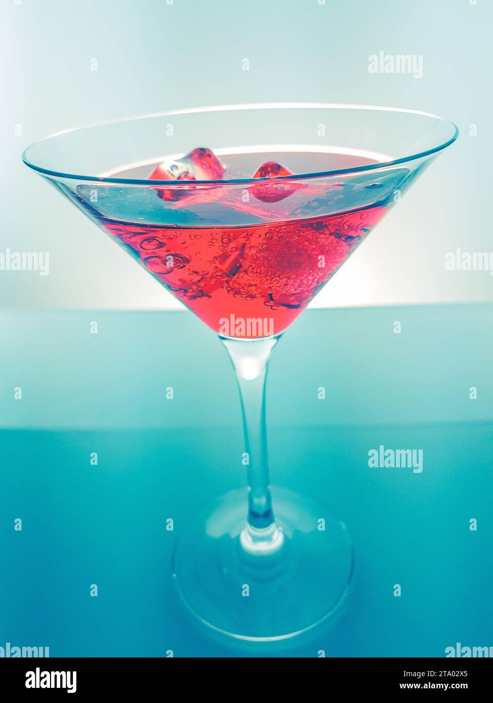 Rotes Cocktail-Getränk mit Eiswürfeln auf grünem Licht, lustiges und tanzendes Disco-Konzept Stockfoto