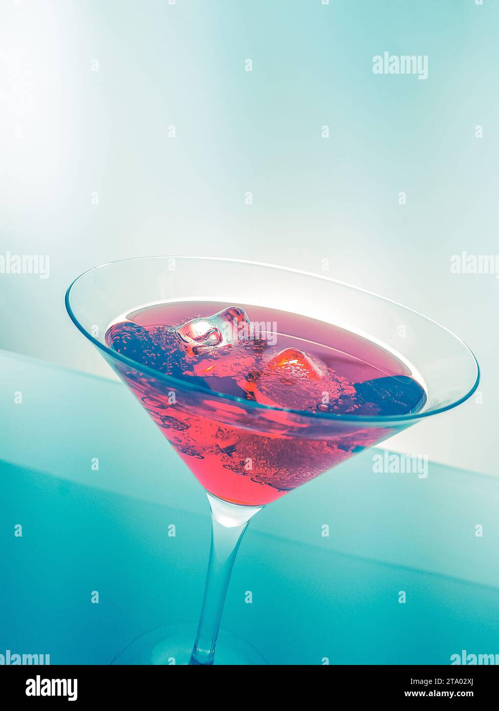Rotes Cocktail-Getränk mit Eiswürfeln auf grünem Licht, lustiges und tanzendes Disco-Konzept Stockfoto