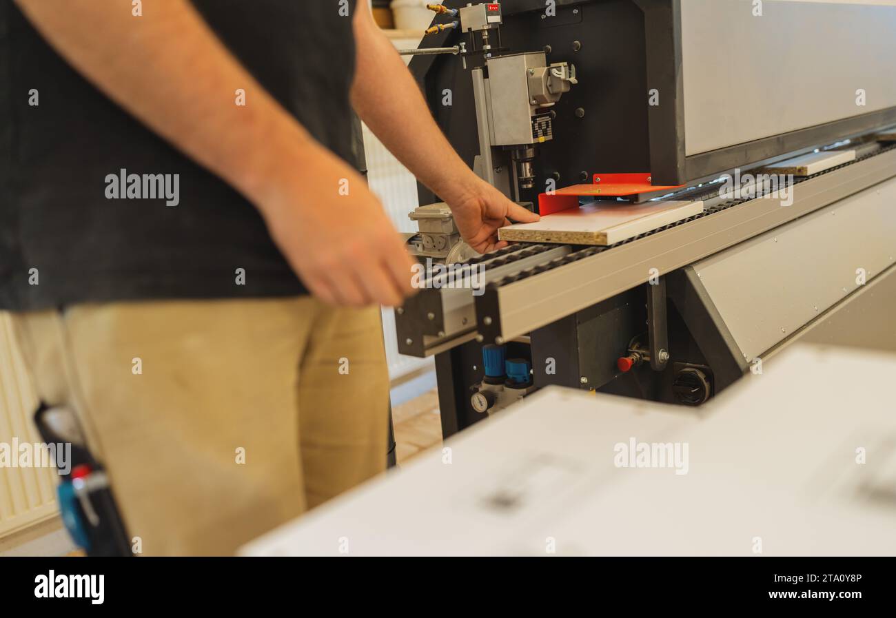 Arbeiter, der Sperrholzplatten in einer Werkstatt auf die Schneidemaschine legt Stockfoto