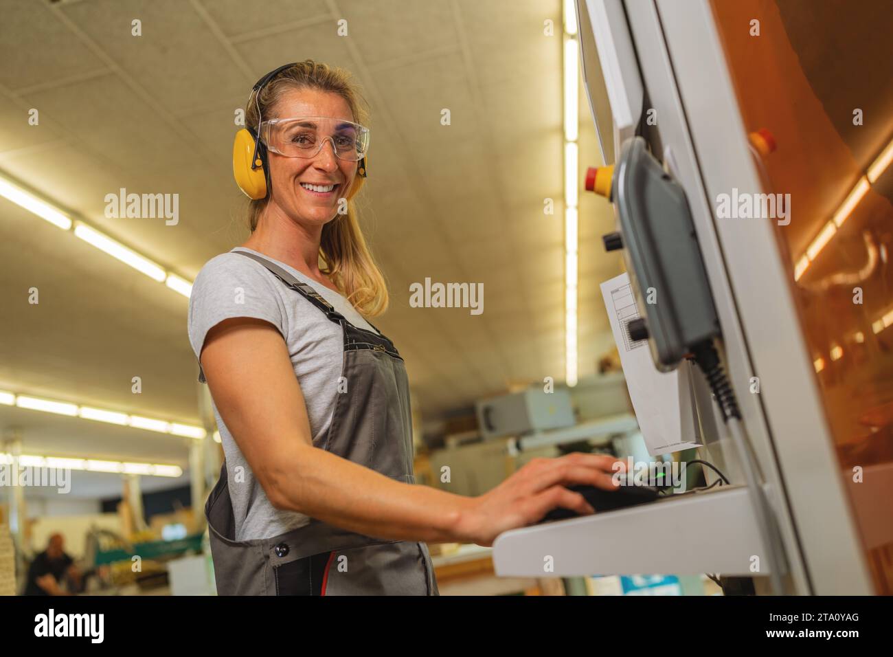 Frau, die einen Computer an einer Schneidemaschine in einer Tischlerei benutzt Stockfoto