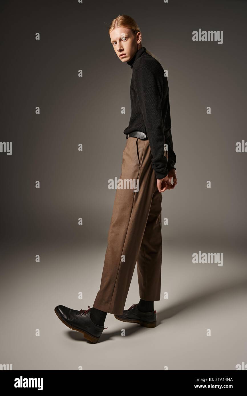 Attraktives, nicht-binäres Modell in eleganter Kleidung mit Pferdeschwanz-Pose mit Armen hinter dem Rücken, Mode Stockfoto