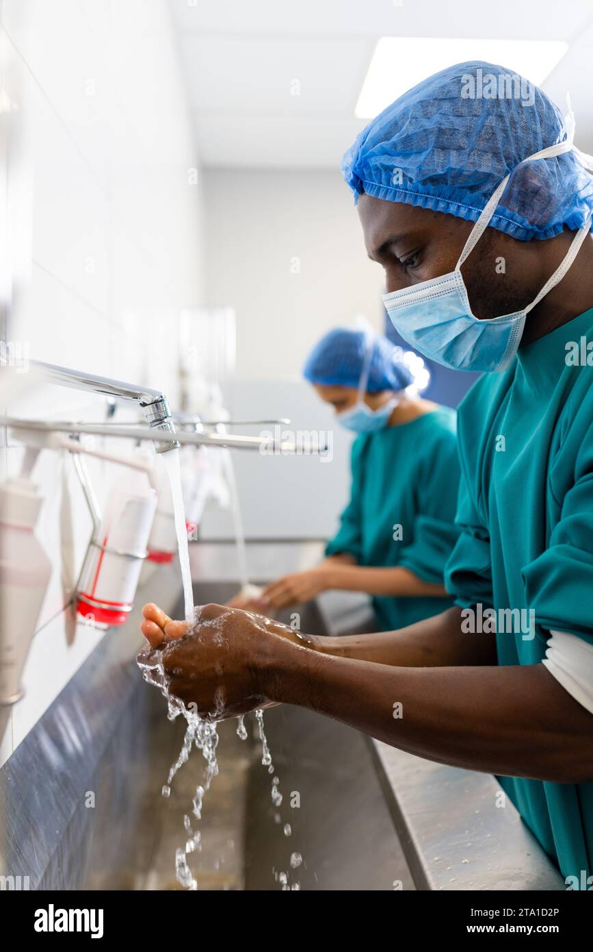 Diverse männliche und weibliche Chirurgen mit Gesichtsmasken beim Händewaschen im Krankenhaus Stockfoto