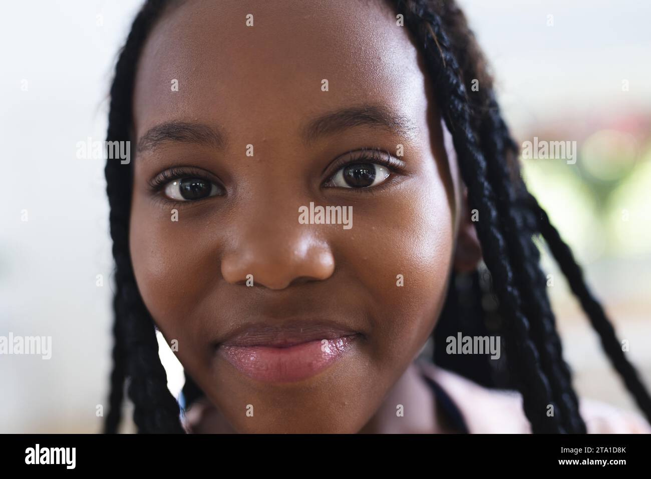 Fröhliches afroamerikanisches Mädchen, das zu Hause lächelt, Gesicht aus der Nähe, Kopierraum. Kindheit, Ausdruck und häusliches Leben unverändert. Stockfoto